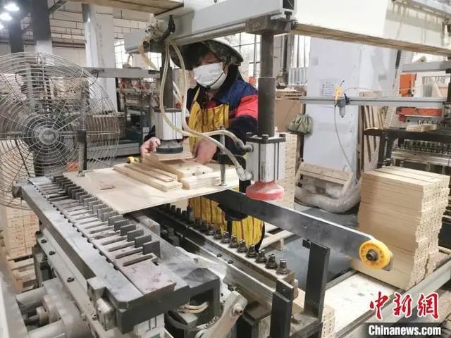 工人正在對(duì)原木板材進(jìn)行打孔處理